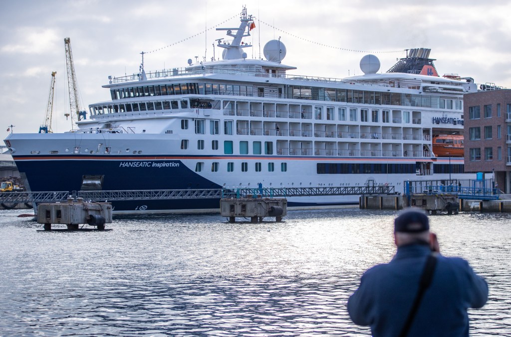 A man photographs the cruise ship Hanseatic Inspiration as it docks in the port of Wismar, Mecklenburg-West Pomerania, marking its first arrival after the forced layoff following COVID.