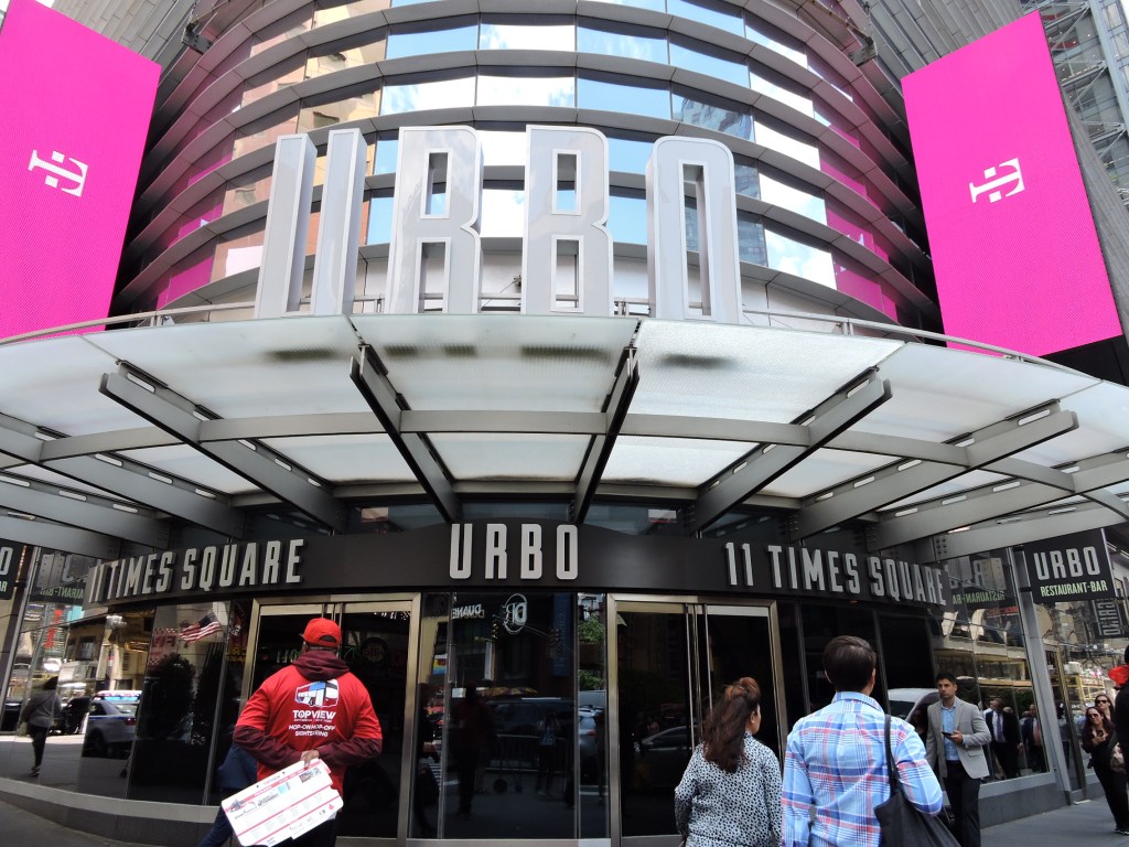 A group of people walk in front of the 11 Times Square building, leased by London-based Path Entertainment